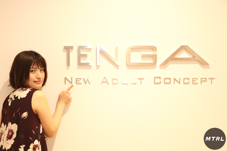 白い壁に「TENGA」のロゴ。素敵なオフィスの象徴の前でポーズを決めるマドカ・ジャスミン。
