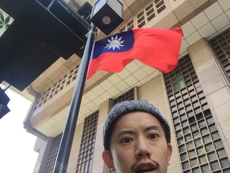 台湾の国旗とともに自撮りする詩人の鈴掛真さん